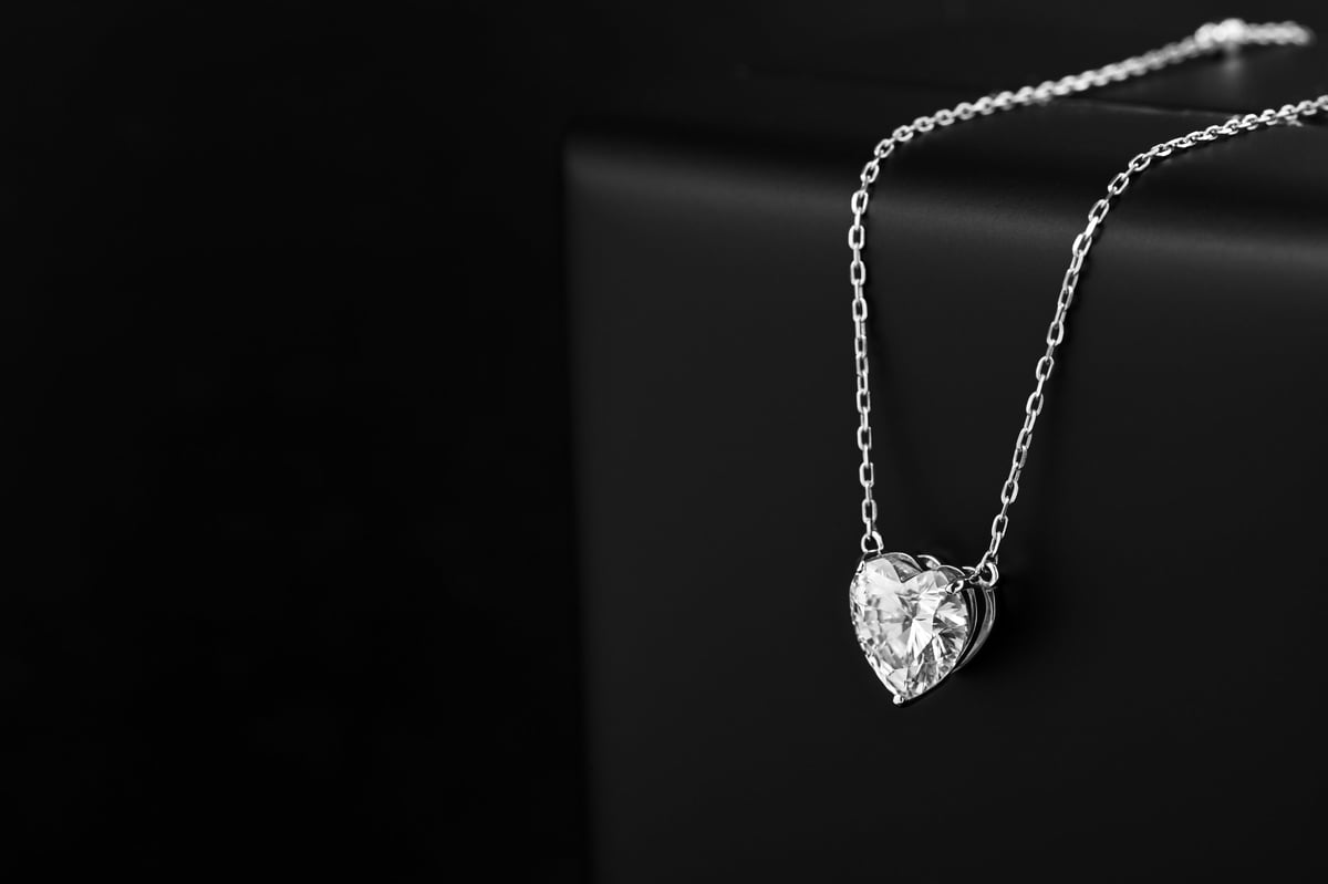 Sølvhalsbånd med hjerteanheng og diamant på en blank overflate